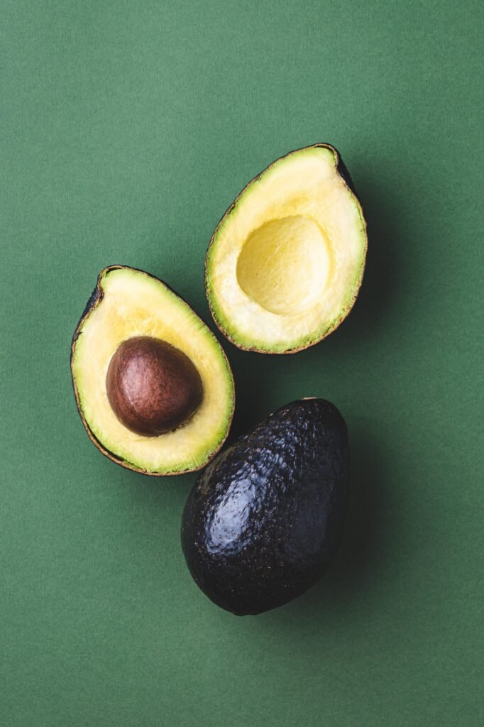 Avocado Hass and Half of Avocado on dark Green Background..