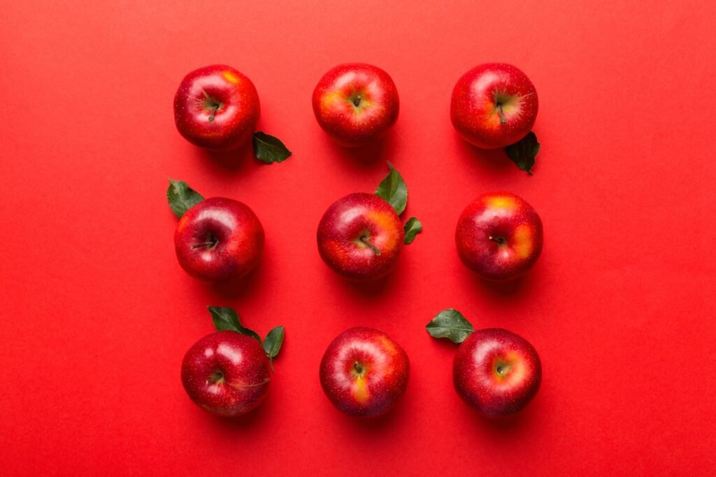 Many red apples on colored background, top view. Autumn pattern with fresh apple